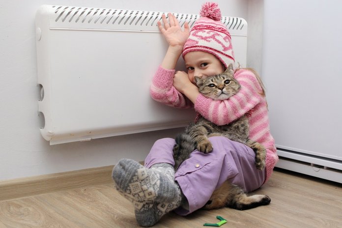 Девочка возле батареи с котом и в шапке