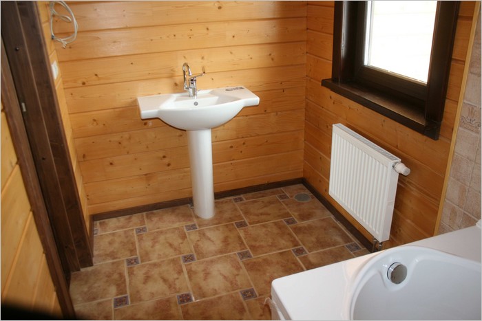 Отделанный плиткой пол ванной комнаты в деревянном доме